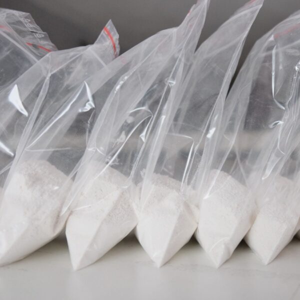 White fentanyl powder sealed in a laboratory sample container, labeled with hazard and controlled substance warnings.