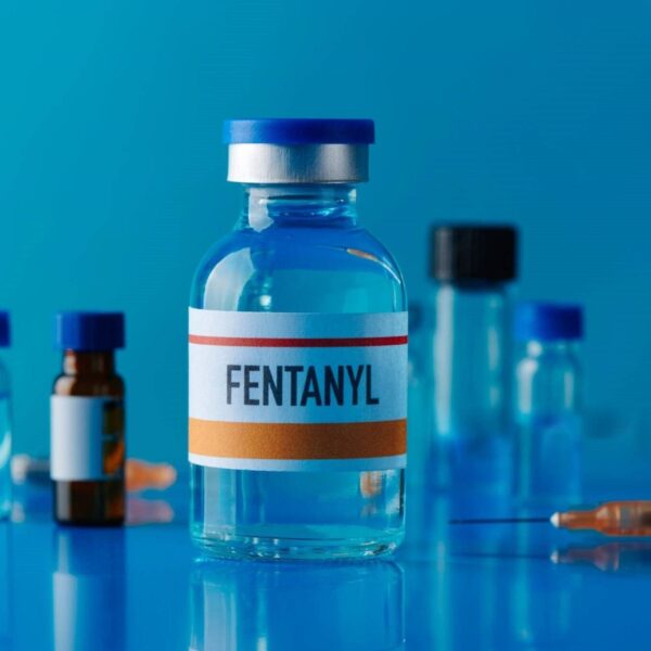 Buy Fentanyl liquid online, a clear glass ampoule of fentanyl injection and a vial of pentobarbital (Nembutal) solution side by side on a sterile surface.
