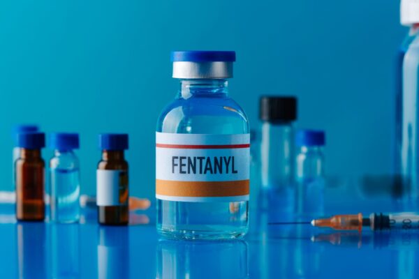 A clear glass ampoule of fentanyl injection and a vial of pentobarbital (Nembutal) solution side by side on a sterile surface.