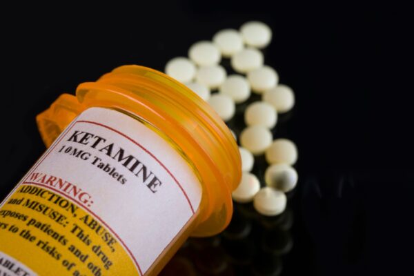 A vial of ketamine with a syringe placed on a sterile surface, used for anesthesia and mental health treatment.
