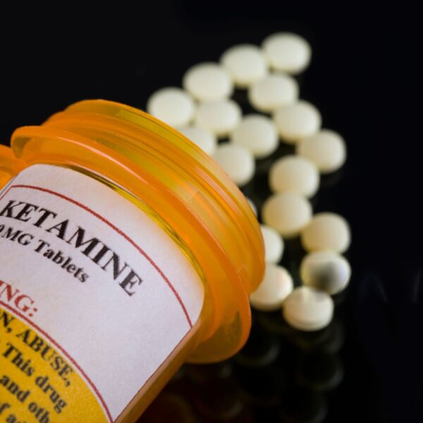 A vial of ketamine with a syringe placed on a sterile surface, used for anesthesia and mental health treatment.